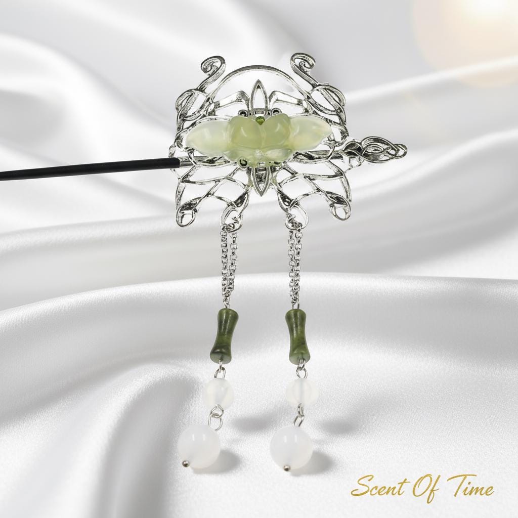Decorative hairpin with green stone and dangling elements on a white background
