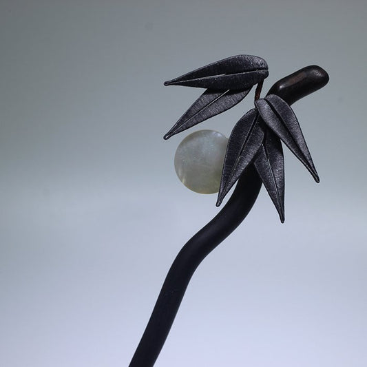 Detail of silk-wrapped bamboo leaf and shell accents on sandalwood hairpin