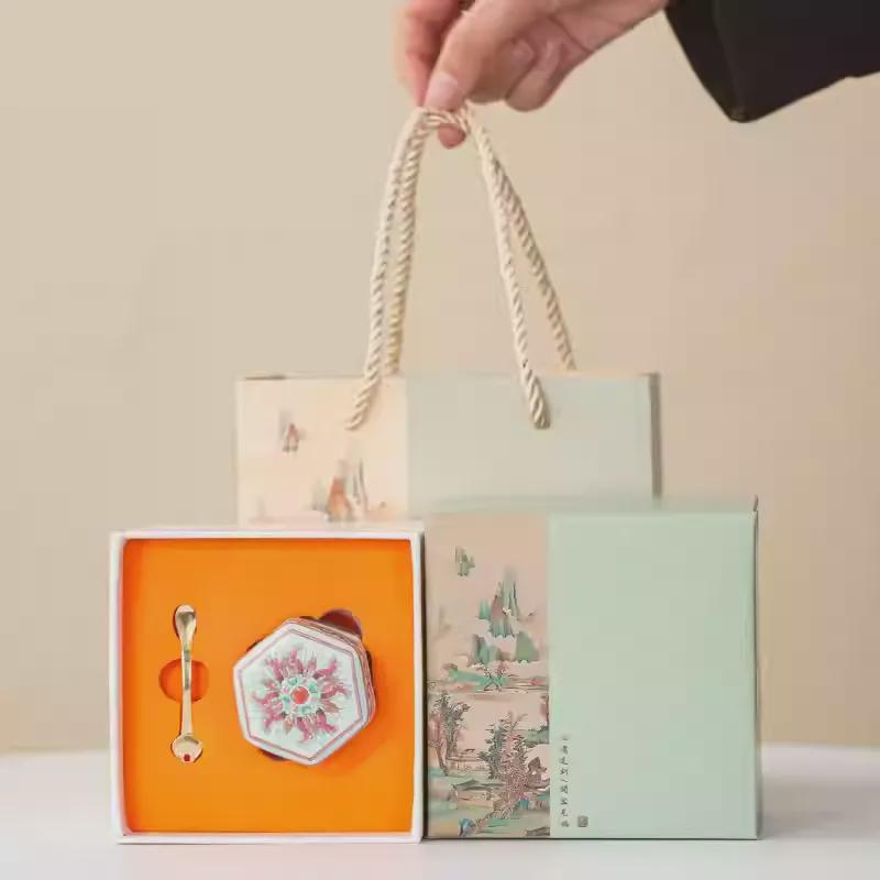 Balm gift box with a hand holding a rope handle against a neutral background