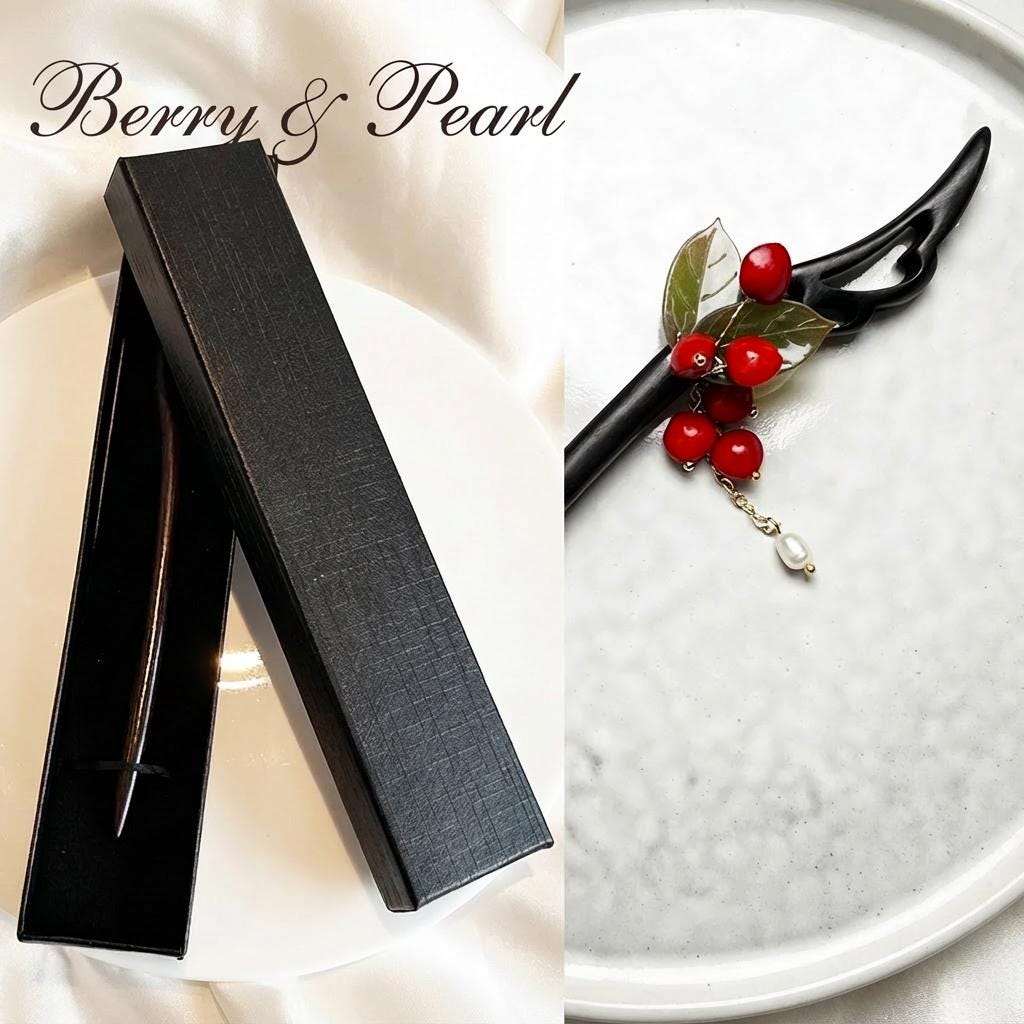 Black hairpin with red berries and pearl on a white plate, next to its packaging, with 'Berry & Pearl' branding.