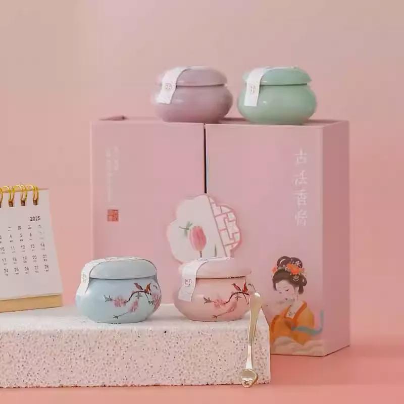 Set of small Balm ceramic containers with lids on a pink box against a pink background