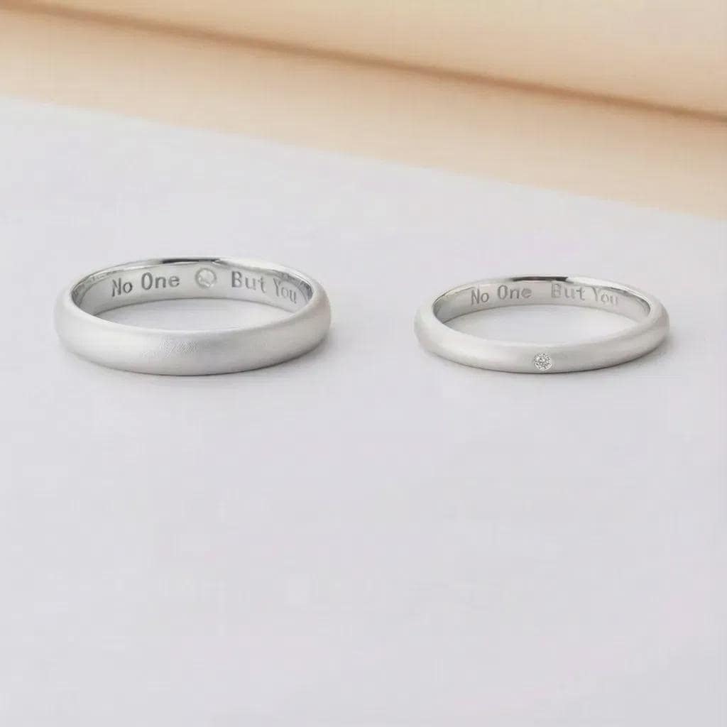Two silver rings with engraved text on a light gray surface