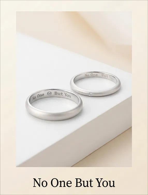 Two silver rings with engraved text on a light beige background
