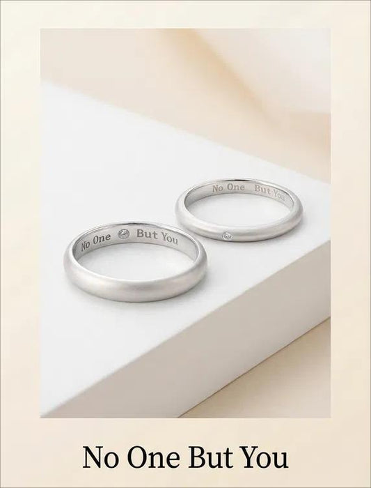 Two silver rings with engraved text on a light beige background