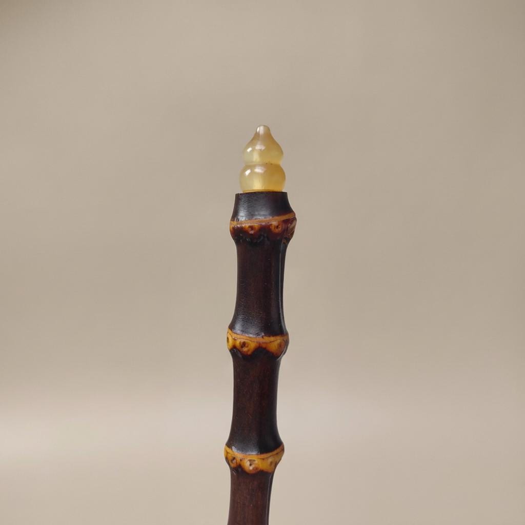Decorative object resembling a bamboo stick with a yellow cap on a beige background