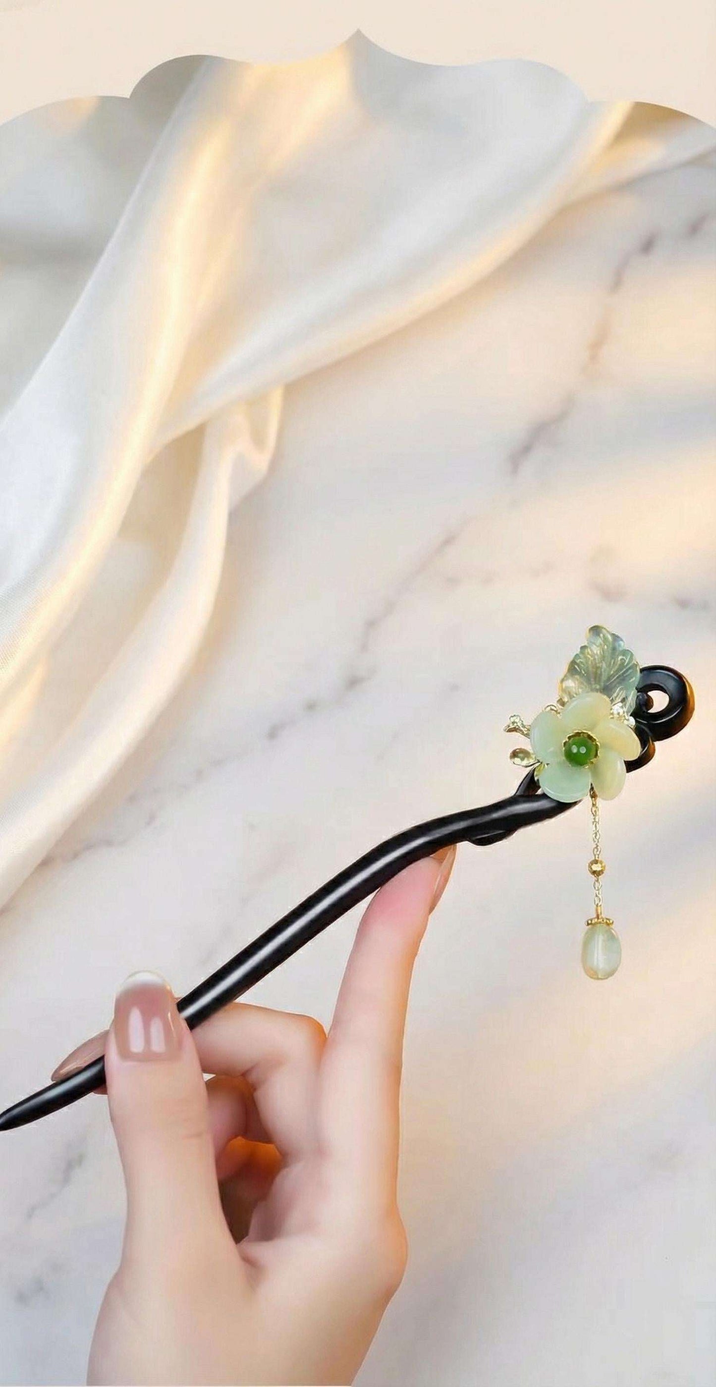 Decorative hair stick with green gemstone on a marble surface
