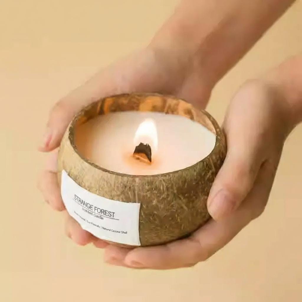 Candle in a coconut shell held by hands against a beige background