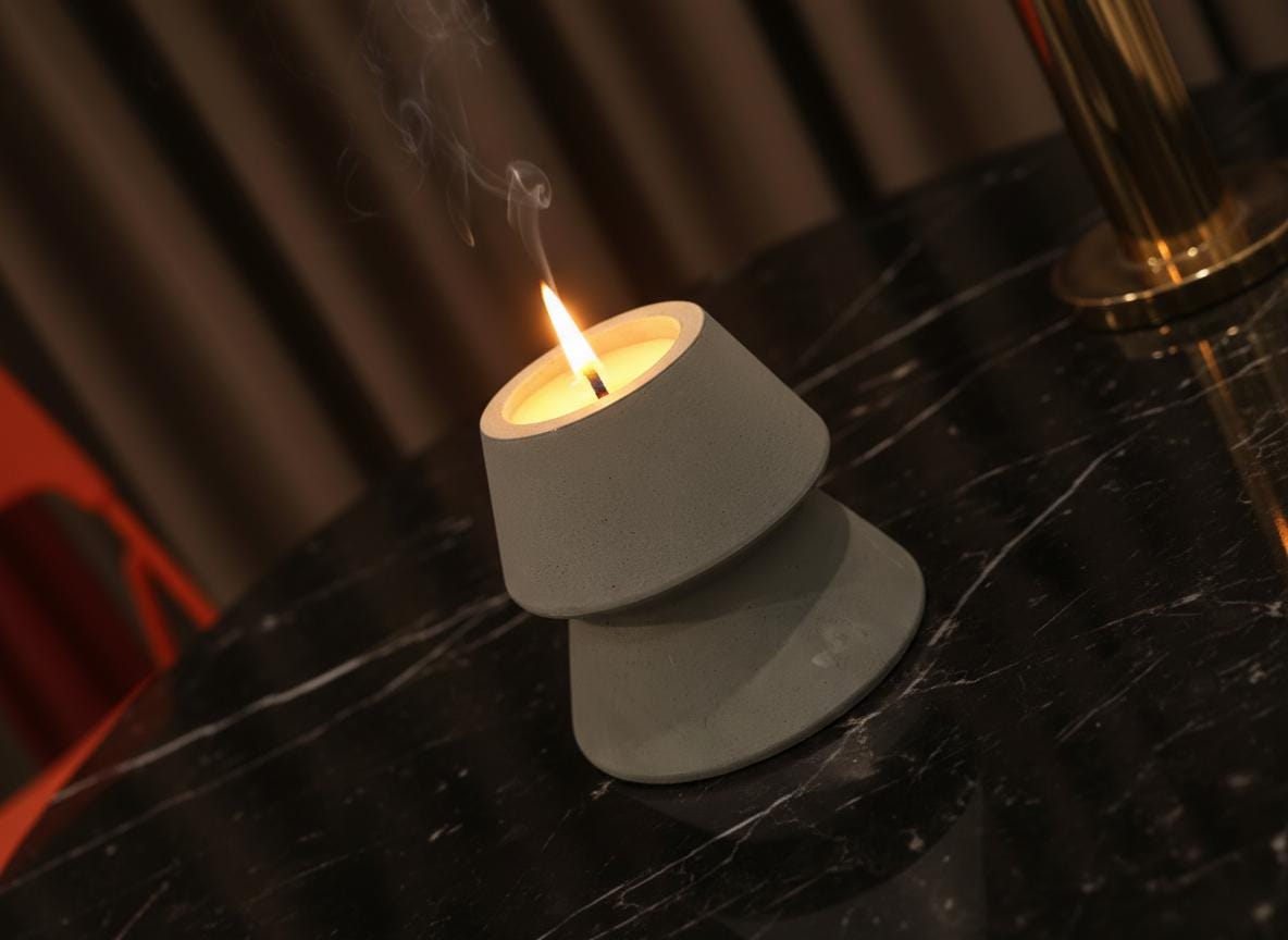 Ceramic candle holder with a lit candle on a dark surface