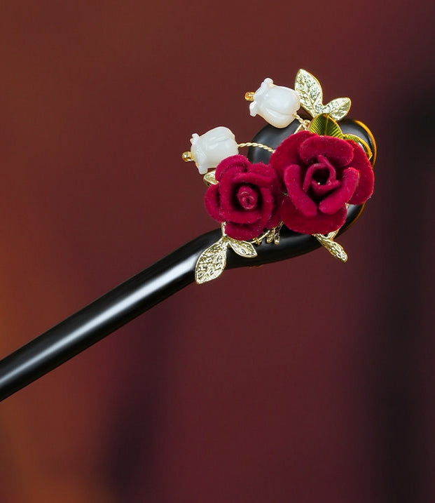Close-up of intricate red rose detail on wooden bridal hair stick