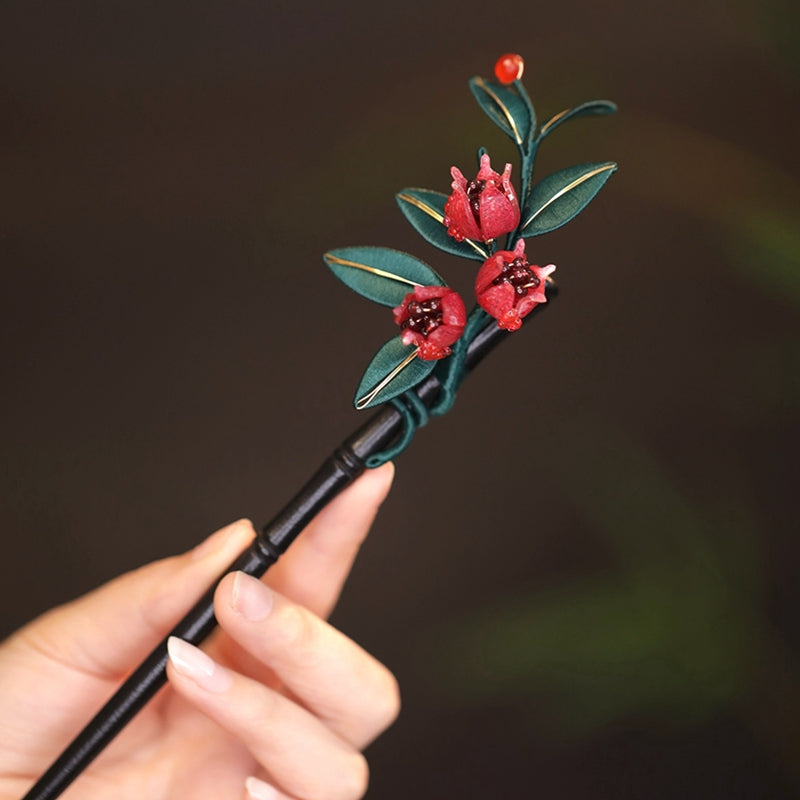 Close-up of traditional Chinese Chanhua (silk-wrapped flower) craftsmanship on a pomegranate hair stick.