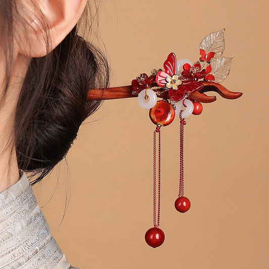 Close-up of traditional Chinese cloisonne and jade butterfly detail on a sandalwood hair stick.