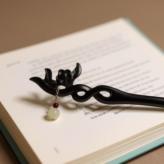 Decorative black hair stick with a Jade pendant on an open book