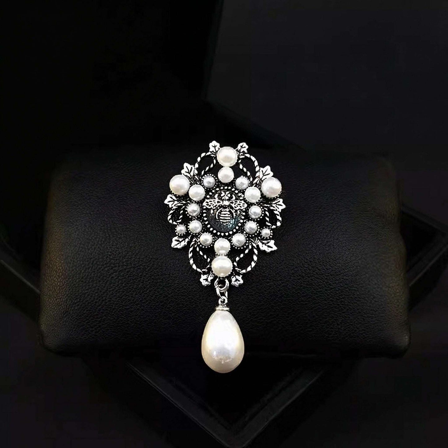 Decorative brooch with pearls on a black cushion