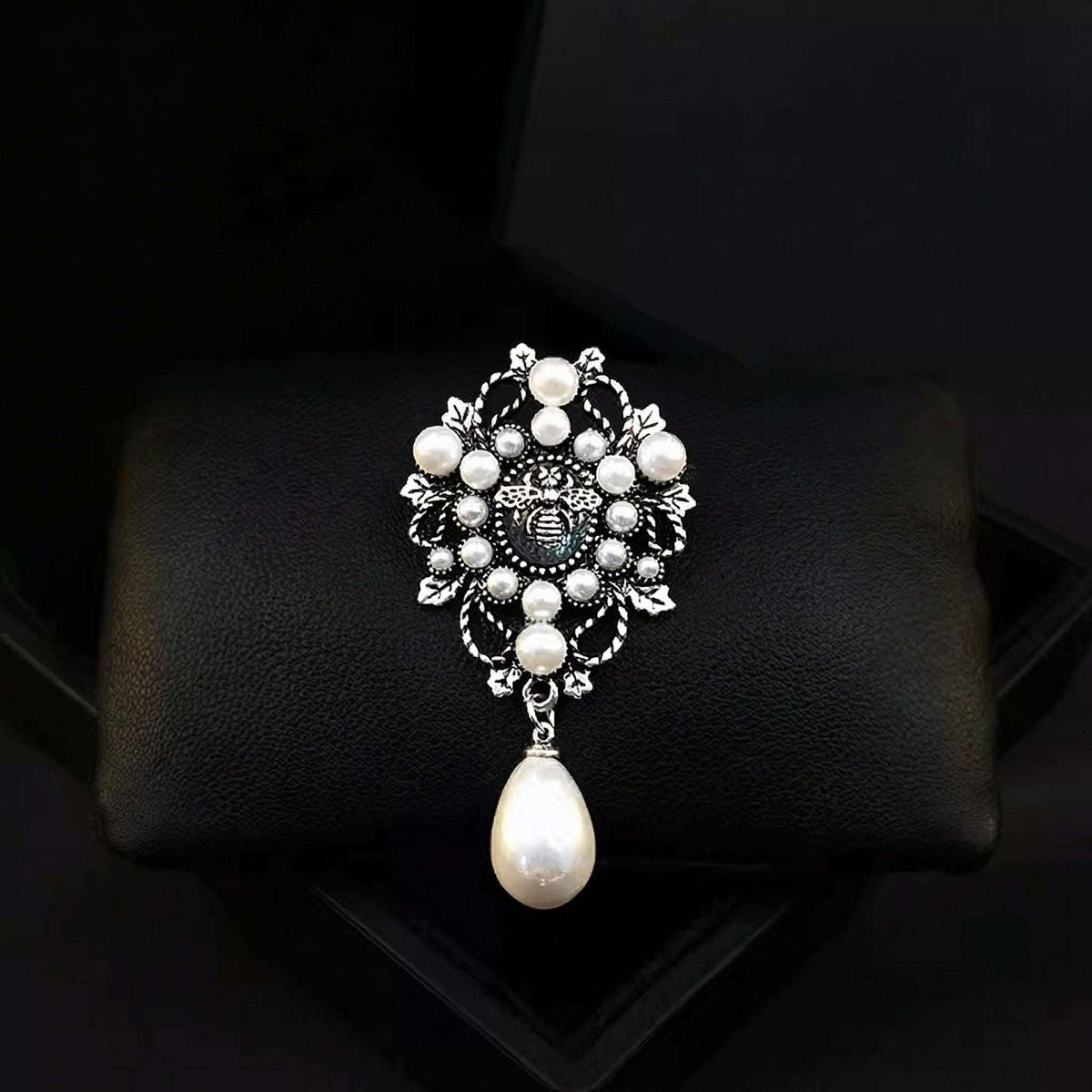 Decorative brooch with pearls on a black cushion