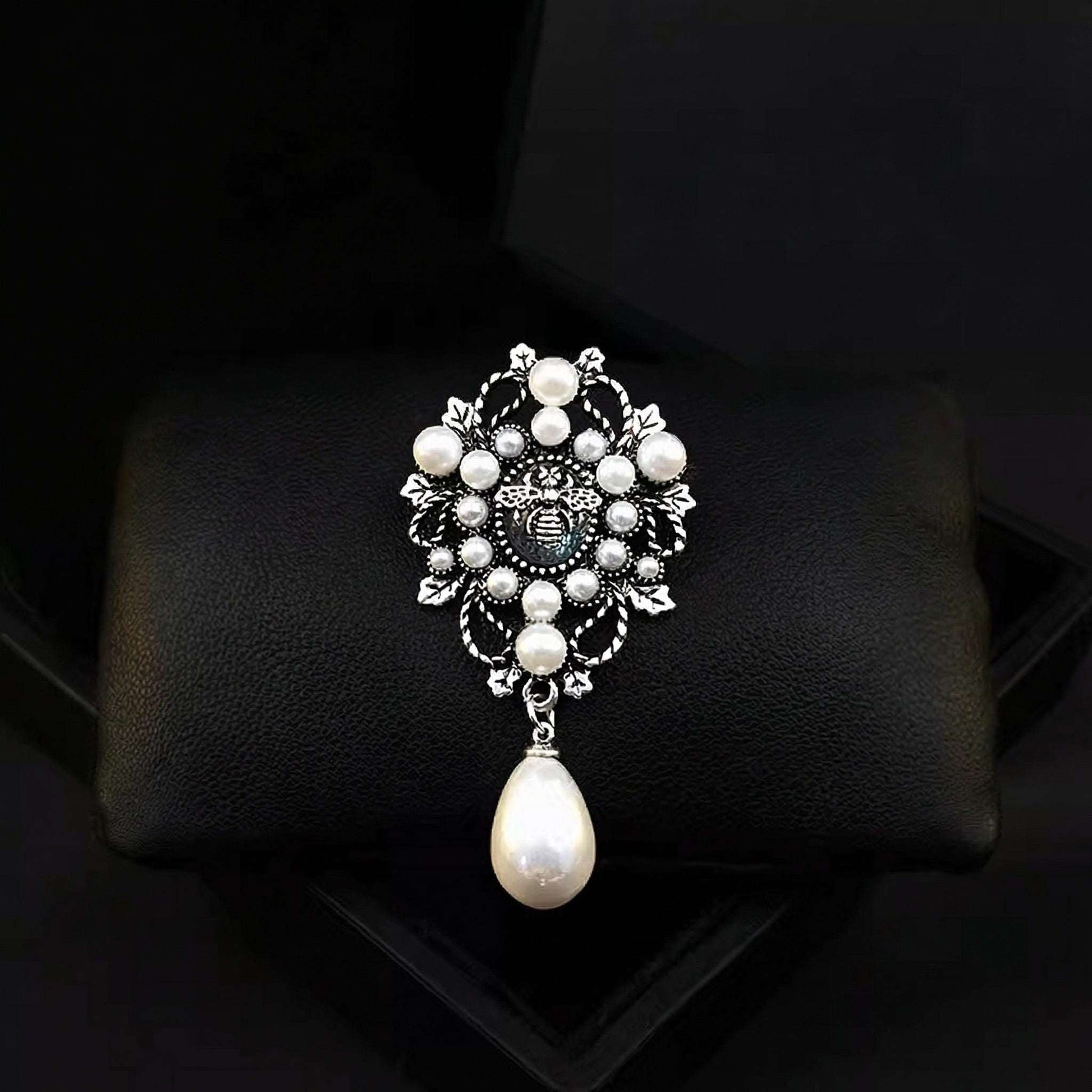 Decorative brooch with pearls on a black cushion