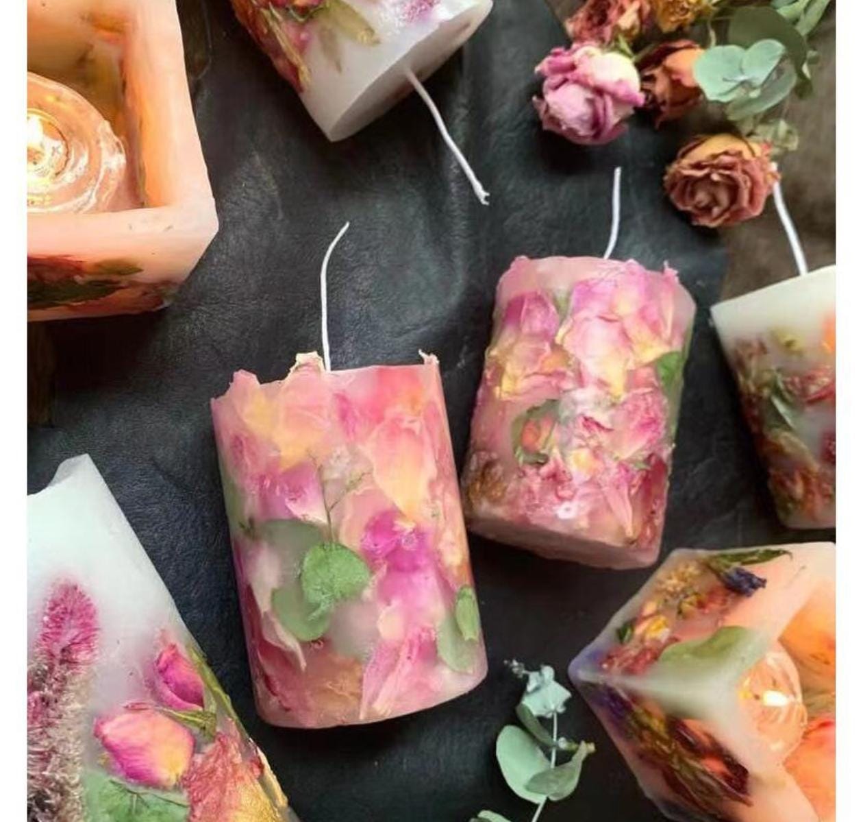 Decorative candles with floral and leaf elements on a dark surface