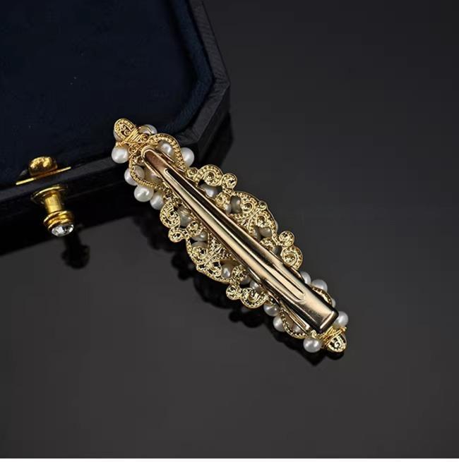 Decorative gold hair clip with pearls on a black background