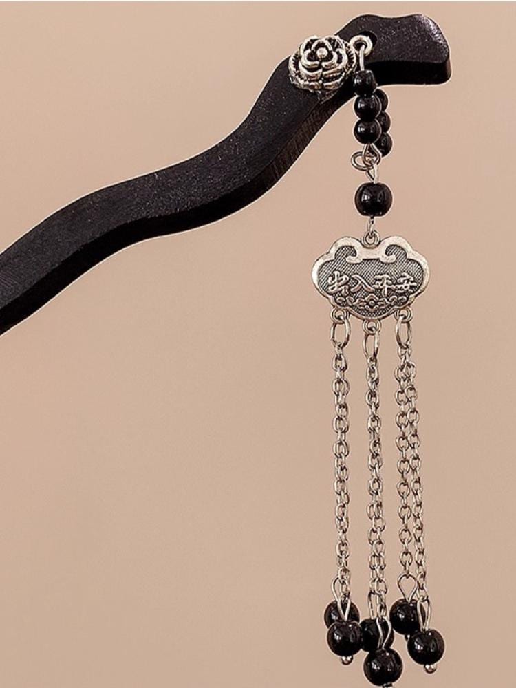 Decorative hair clip with black beads and silver chain on a beige background