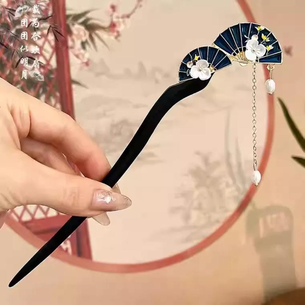 Decorative hairpin with floral design held by a hand against a blurred background