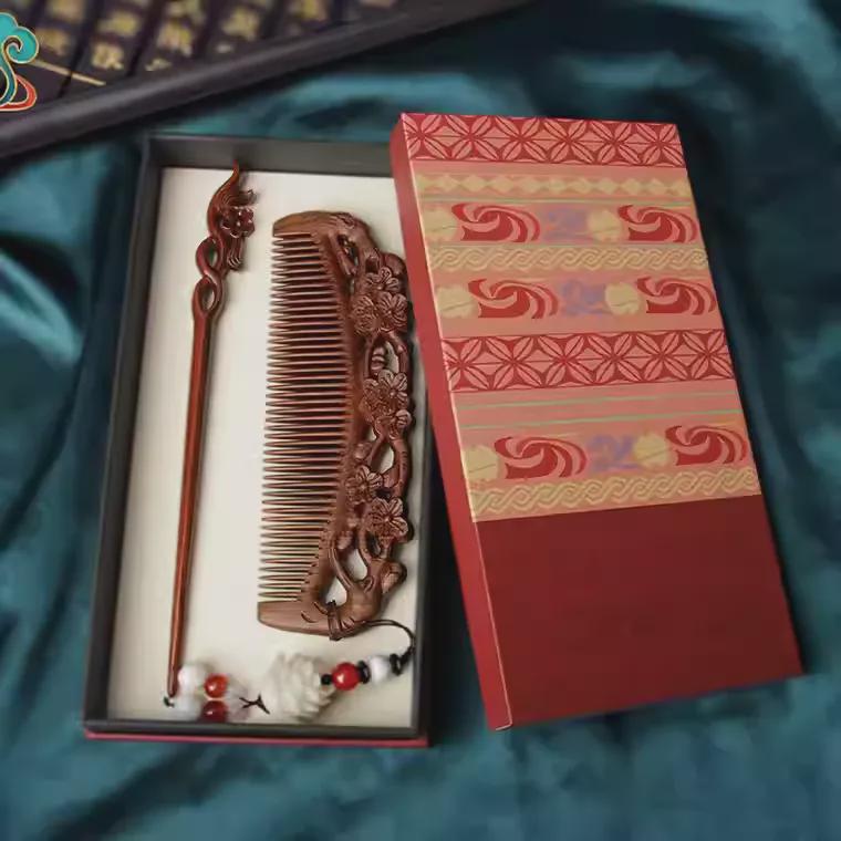 Decorative wooden comb and hairpin set in a patterned box on a blue fabric background