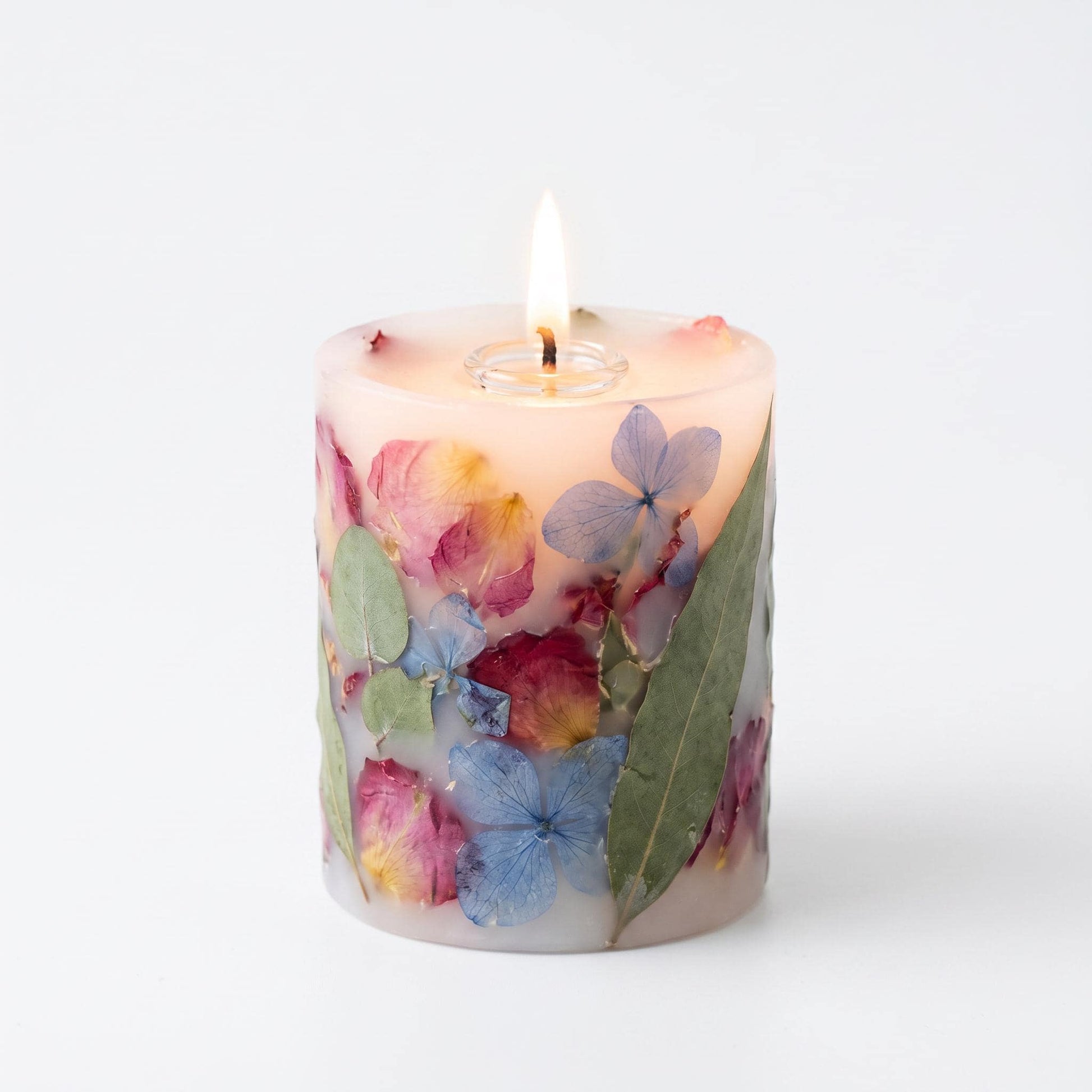 Floral-patterned candle with a lit wick on a white background