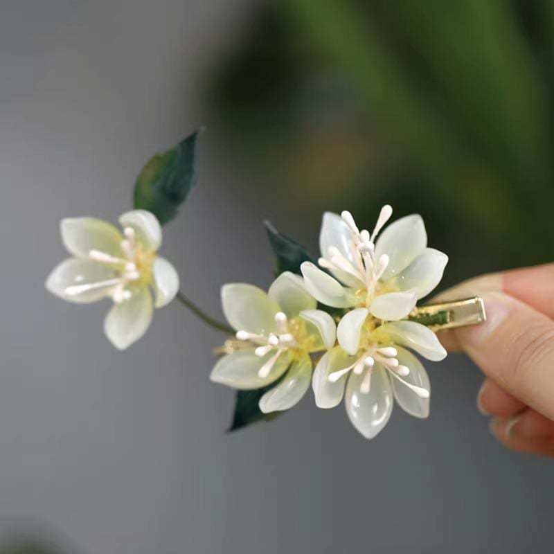 Floral hair clip held by a hand against a blurred background