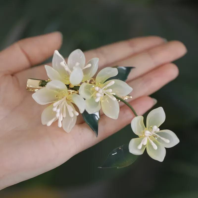 Floral hair clip held in a hand with a blurred green background