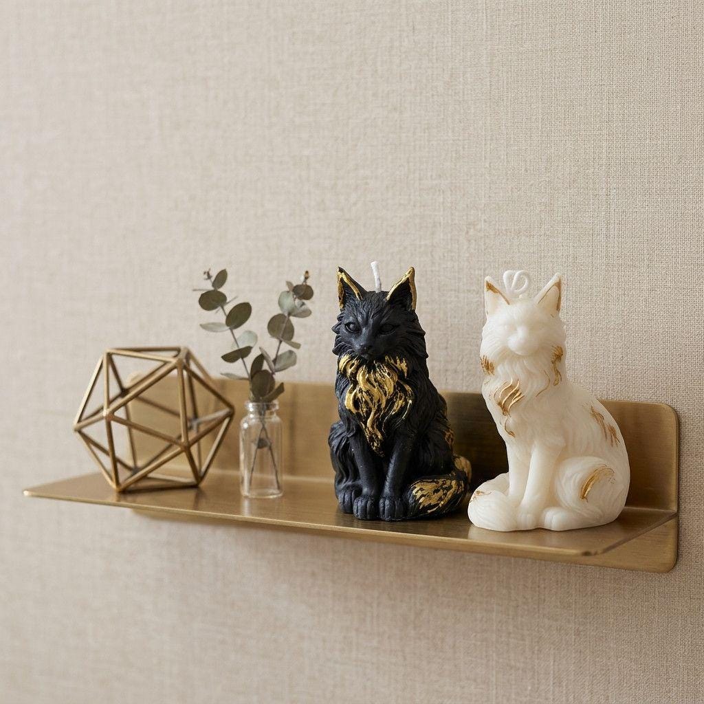 Decorative shelf with geometric candle holder, glass vase with eucalyptus, black cat-shaped candle, and white dog-shaped candle against a beige wall.