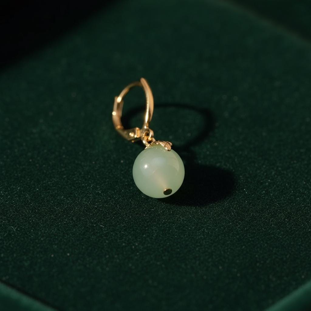 Gold earring with a green gemstone on a dark green background