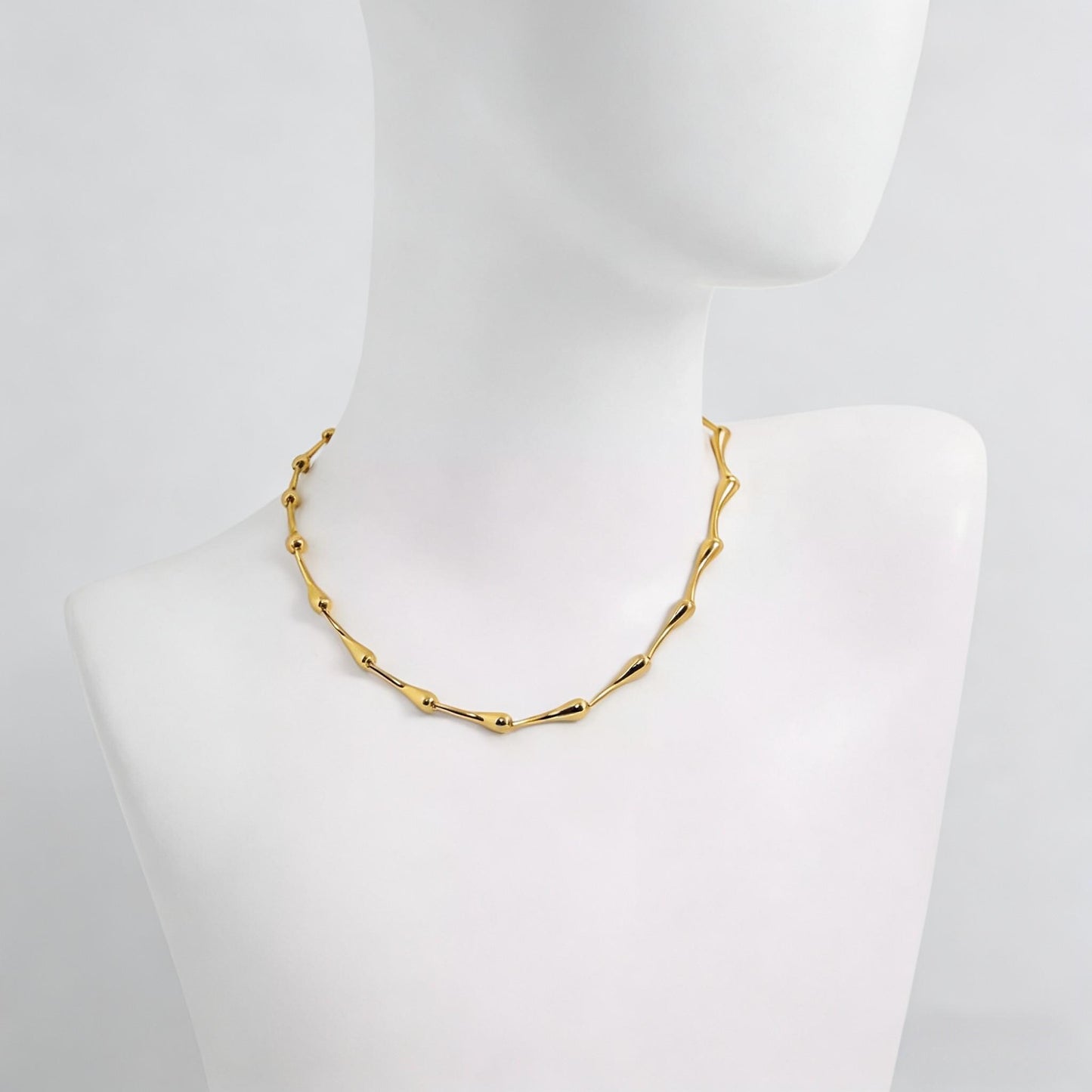 Gold necklace on a mannequin with a plain background