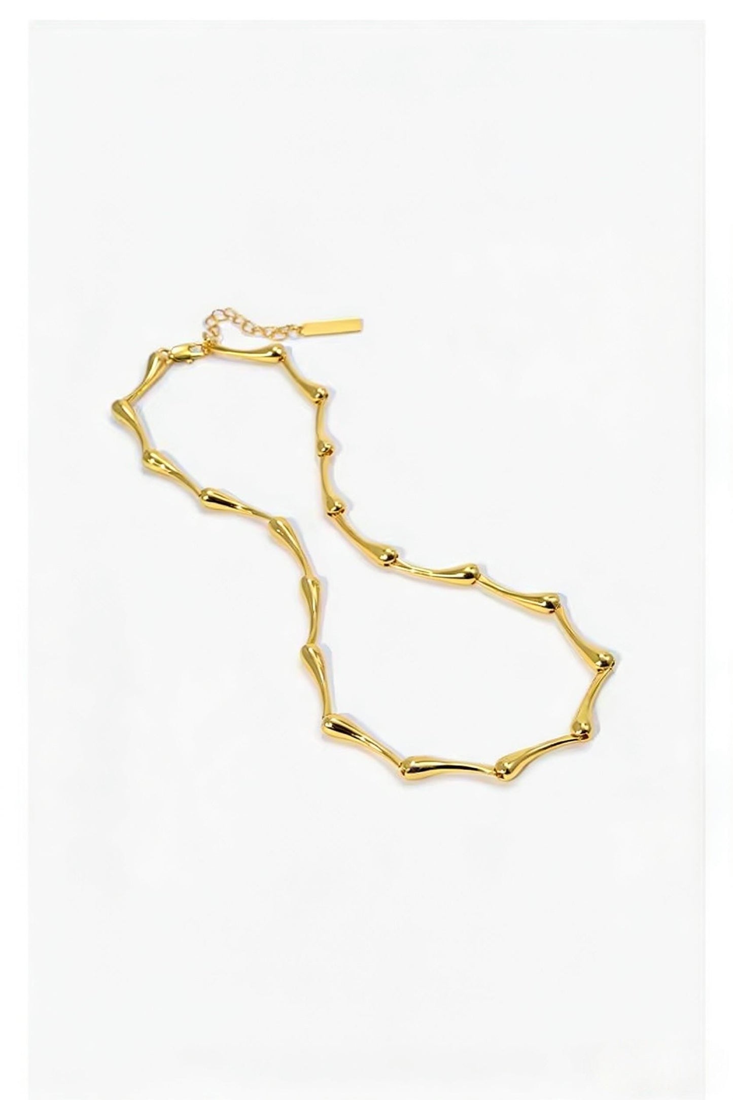 Gold water drops necklace on a white background