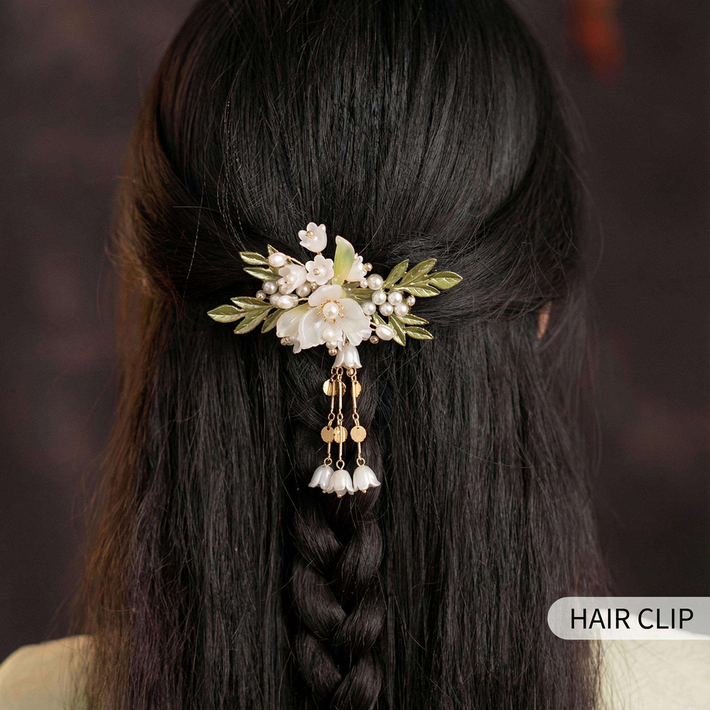 Hair clip with floral design in a braided hairstyle against a dark background