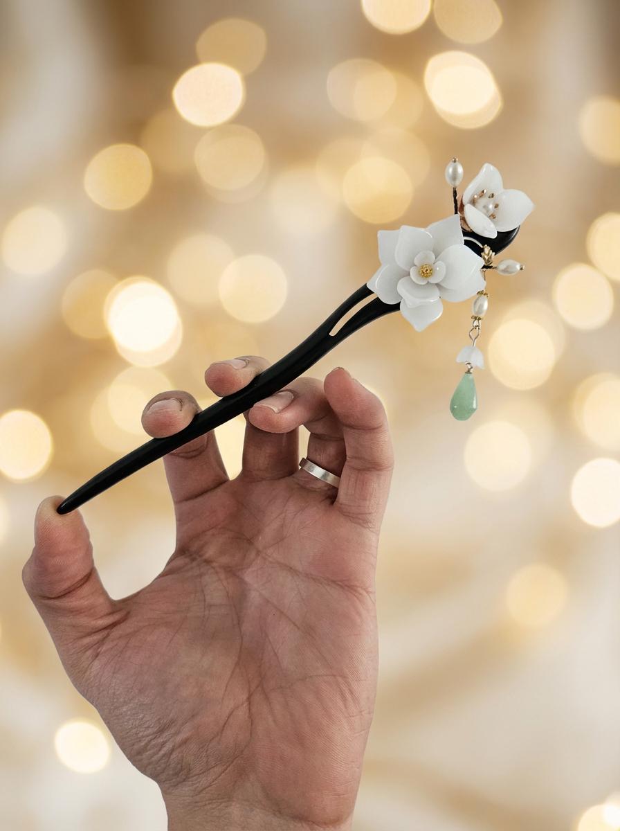 Hand holding a decorative hair stick with floral design against a blurred light background