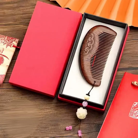 Wooden comb with decorative elements in a red box on a wooden surface