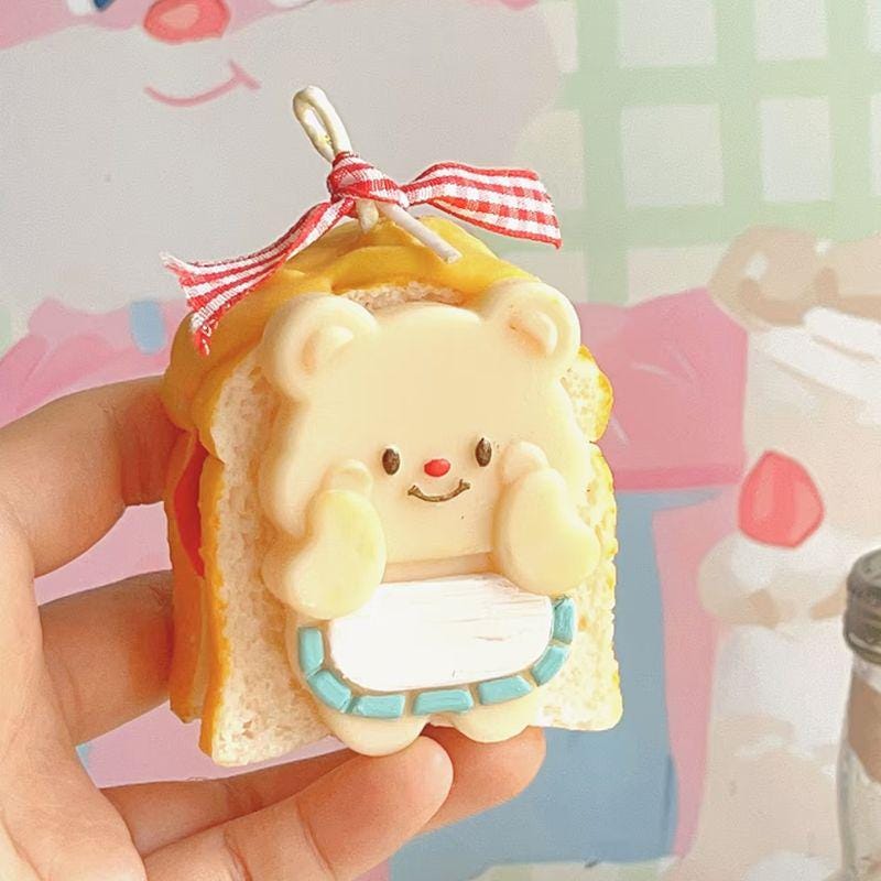 Small bear-shaped toast figurine with a bow held in a hand against a colorful background