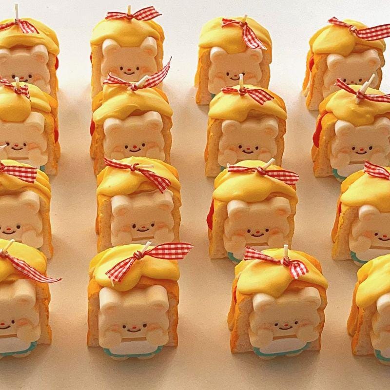 Row of cartoonish bread figurines with yellow hair and red bows on a light background