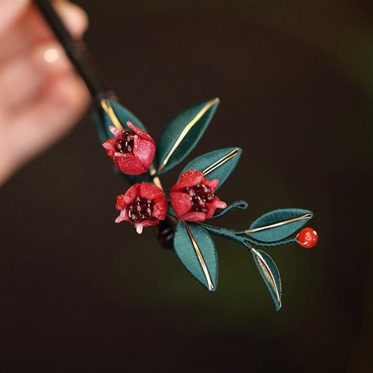 Handmade Chanhua pomegranate flower hairpin with red silk-wrapped petals and green leaves.