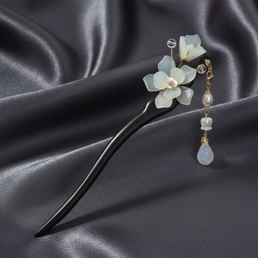Decorative hair pin with floral design and beads on a dark fabric background