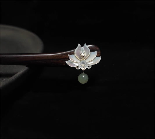 Decorative hair stick with lotus design and pearl on a dark background