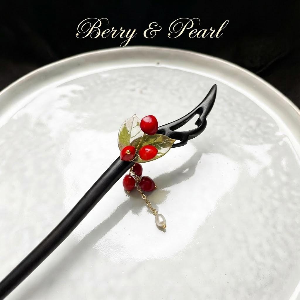 Decorative hair stick with red berries and a pearl on a white plate, branded 'Berry & Pearl'.