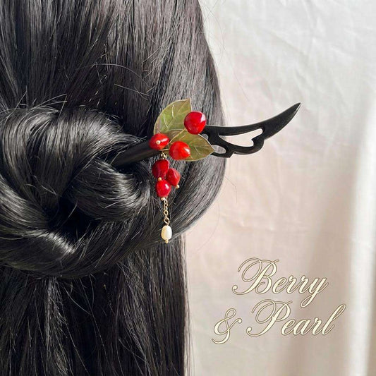 Hair accessory with red berries and a pearl on black hair against a white background, featuring the brand 'Berry & Pearl'.
