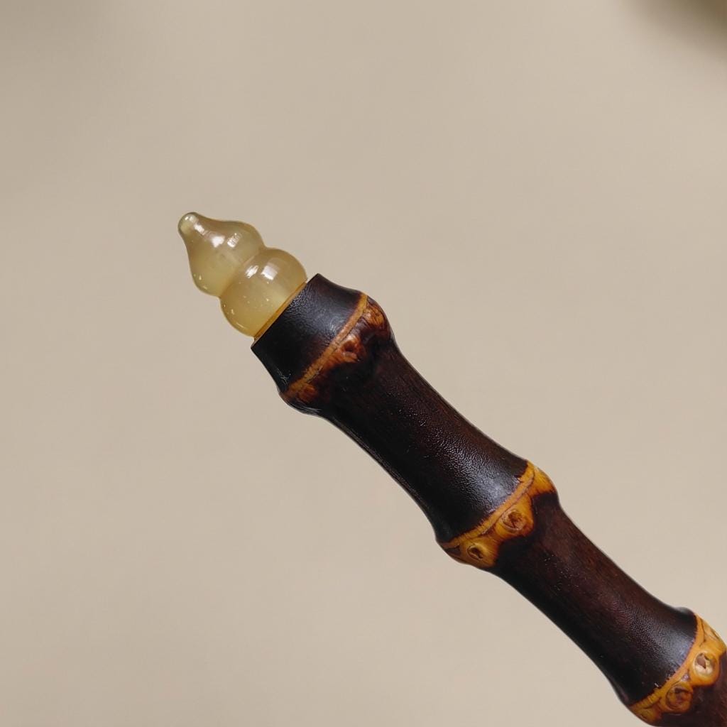 Close-up of a decorative object with a brown and black handle and a yellow top on a beige background.