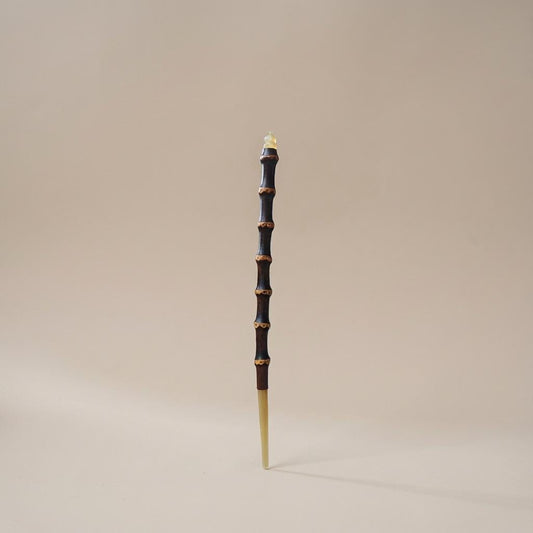 Decorative staff with black and gold design on a beige background