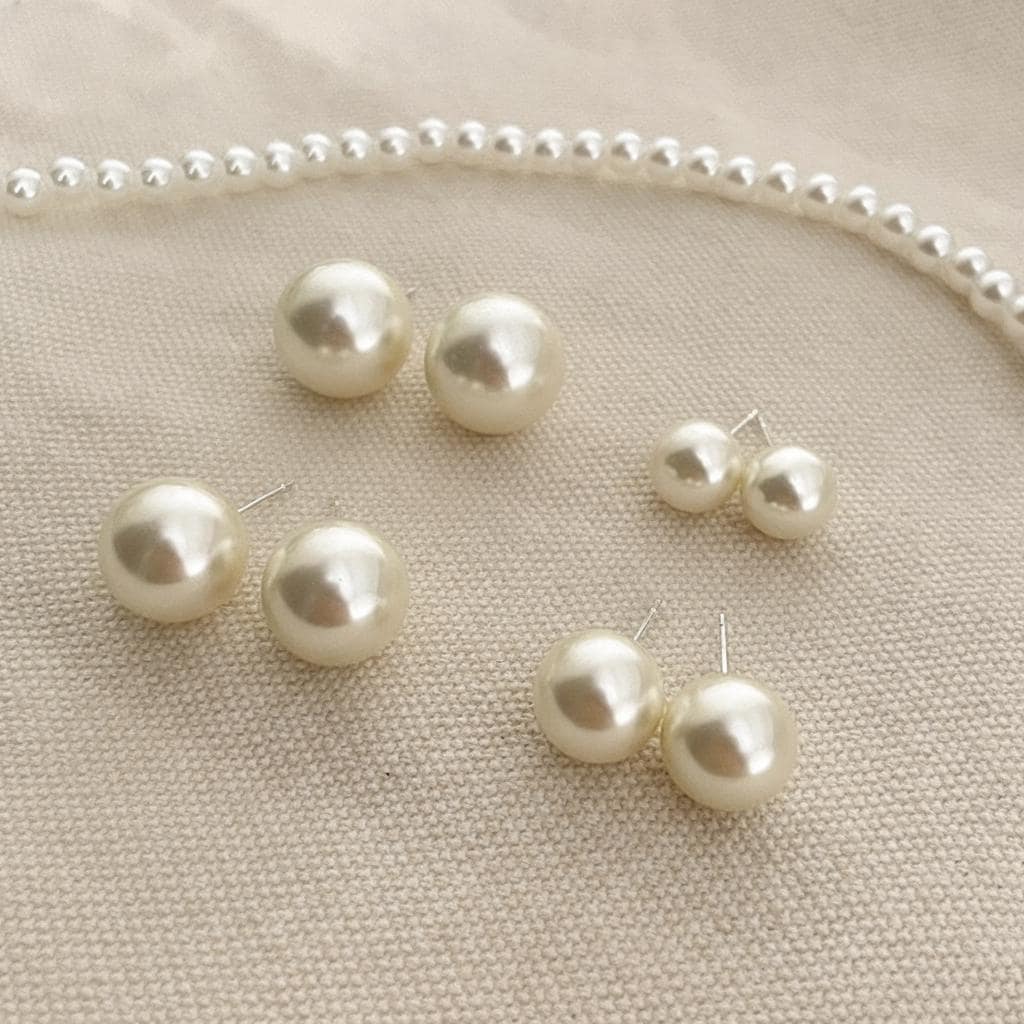 Pearl necklace and earrings on a beige fabric background
