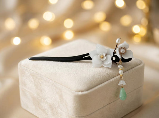 Decorative hairpin with flowers and beads on a textured surface with blurred lights in the background