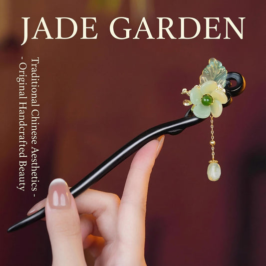 Handcrafted hairpin with floral design held by a hand, branded 'Jade Garden' on a blurred background.