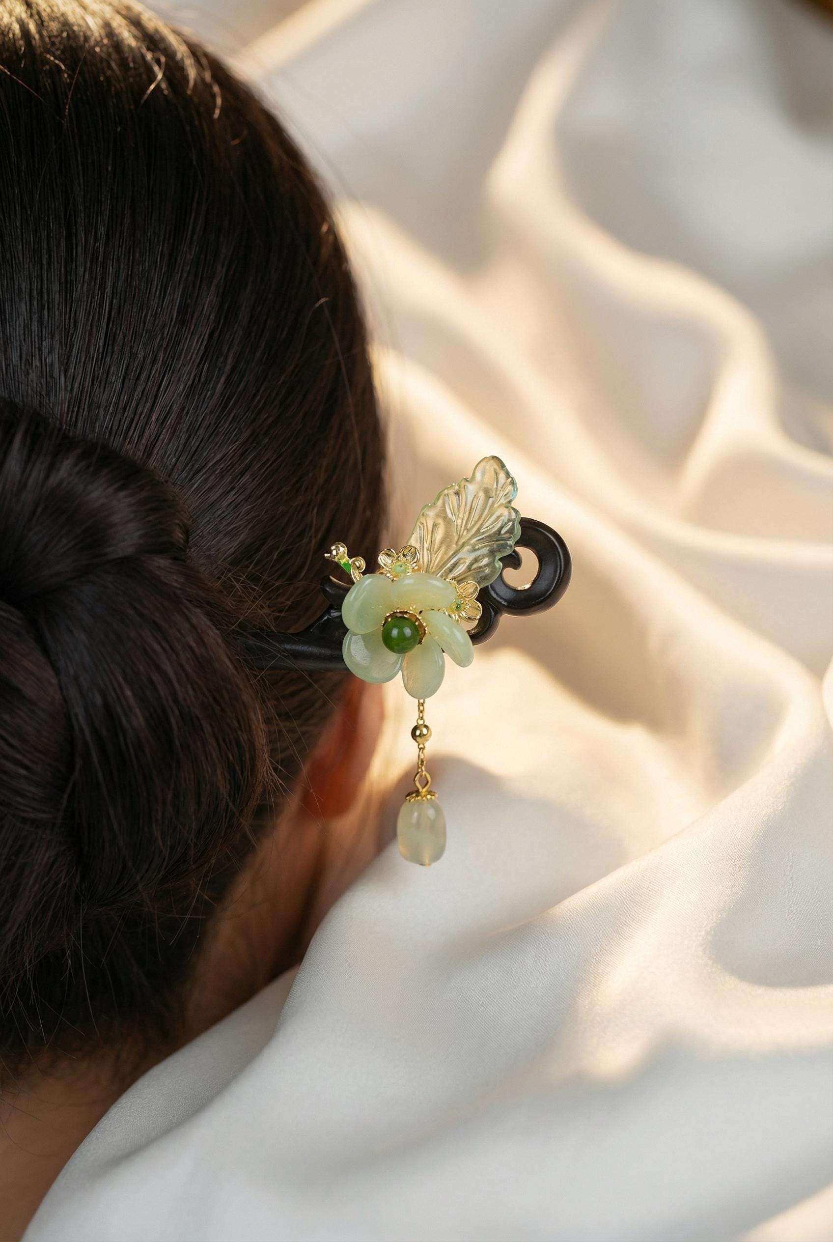 Decorative hair clip with floral design and green gemstone on a person's hair against a soft white background