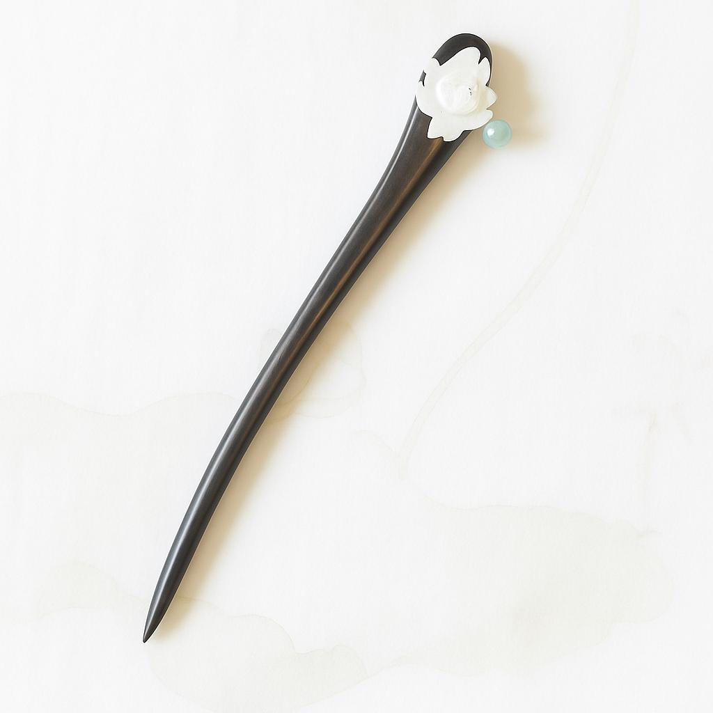 Black hairpin with white flower and green bead on a white background