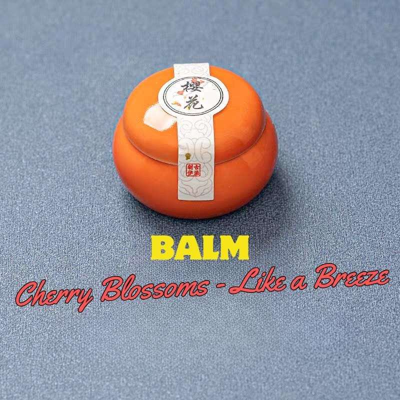 Orange balm with a label on a blue background, labeled 'Cherry Blossoms - Like a Breeze'