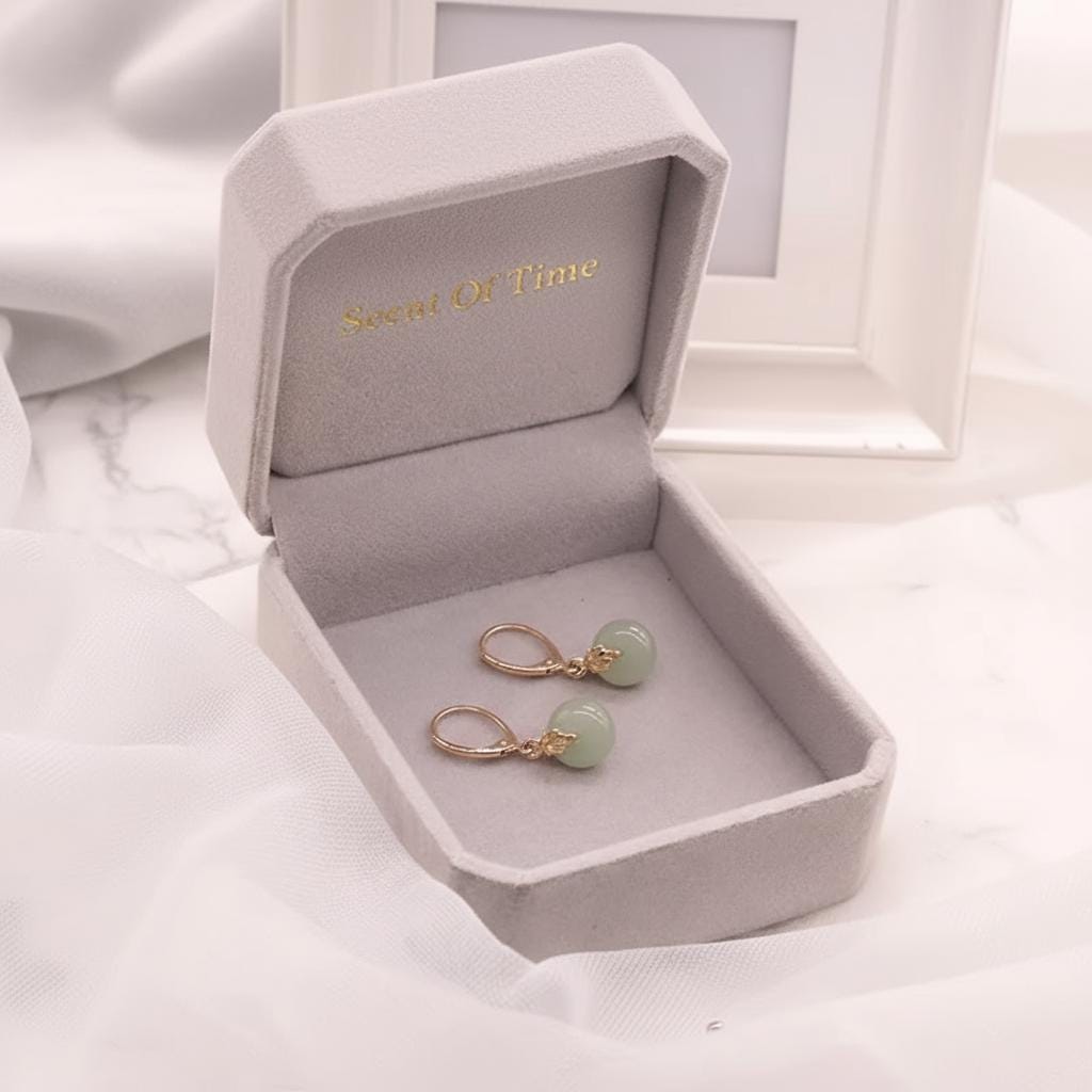 Pair of earrings in a 'Secret of Time' jewelry box on a white fabric background